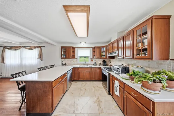 a large kitchen with stainless steel appliances granite countertop a lot of counter space and a window