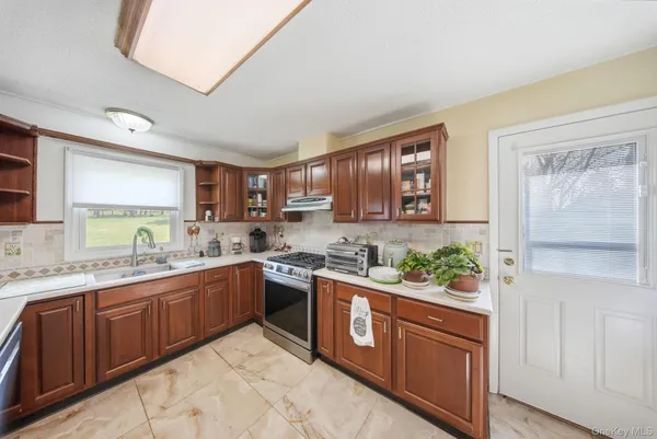 a kitchen with stainless steel appliances granite countertop a sink stove and wooden cabinets