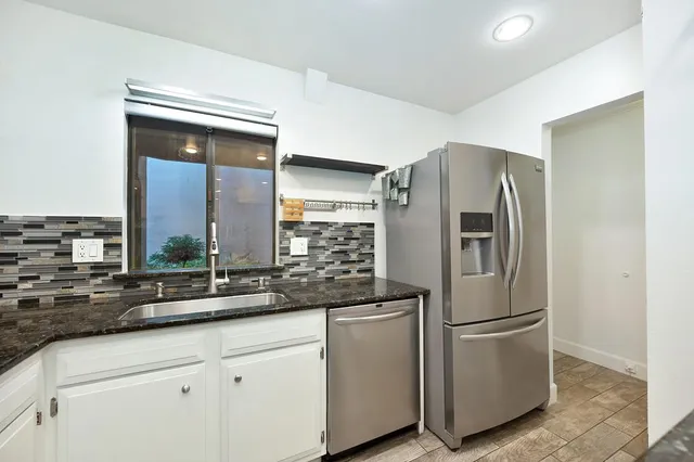 a kitchen with stainless steel appliances granite countertop a refrigerator and a sink