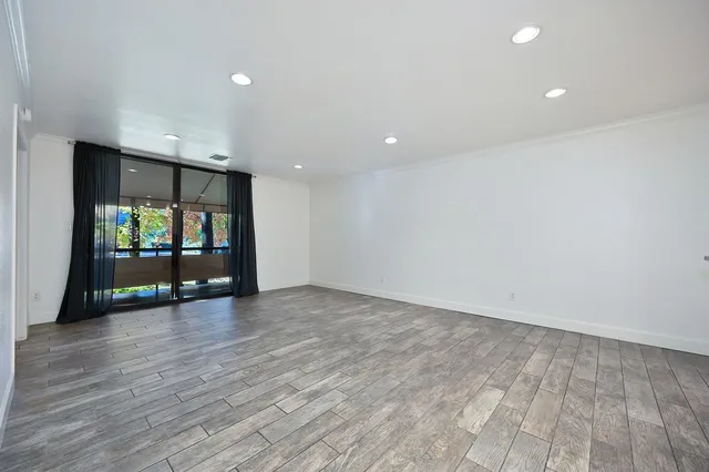 a view of an empty room with wooden floor and windows
