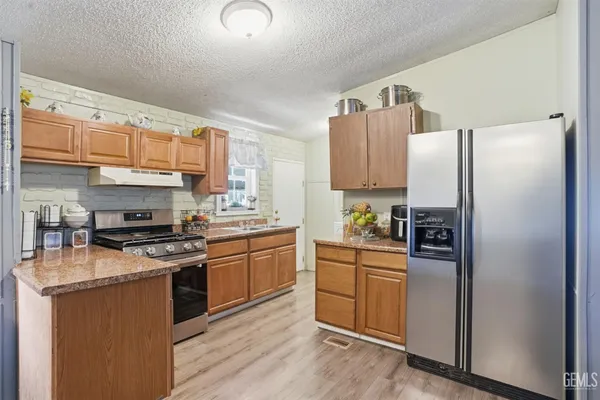 a kitchen with stainless steel appliances a dining table chairs stove and refrigerator