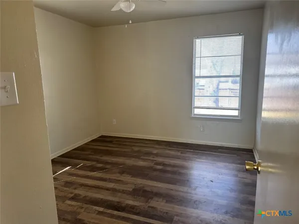 an empty room with wooden floor cabinet and windows