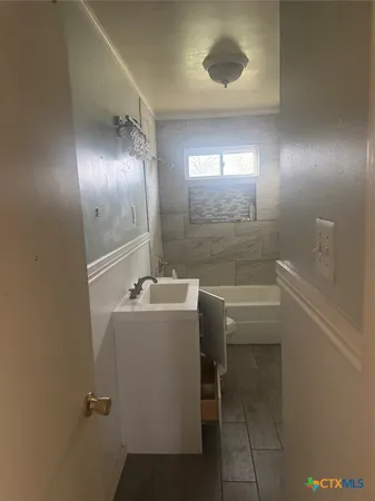 a bathroom with a sink and mirror with bathtub