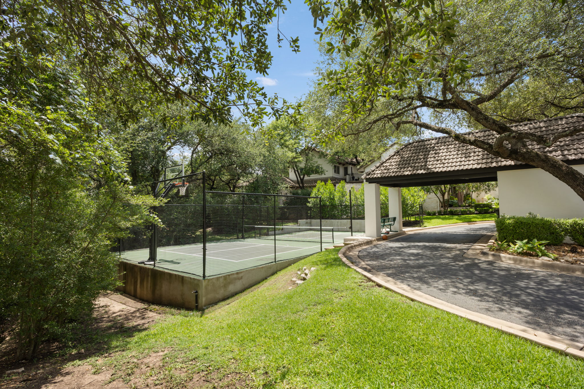 1910 Rue De St Tropez, Unit 6 Austin, TX 78746 - Photo 33 of 37 A private basketball court nestled amongst mature trees, with a covered entrance leading to the property.