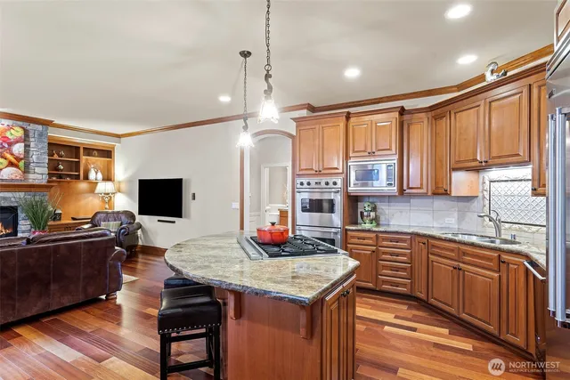 a kitchen with a stove a sink dishwasher a dining table and chairs with wooden floor