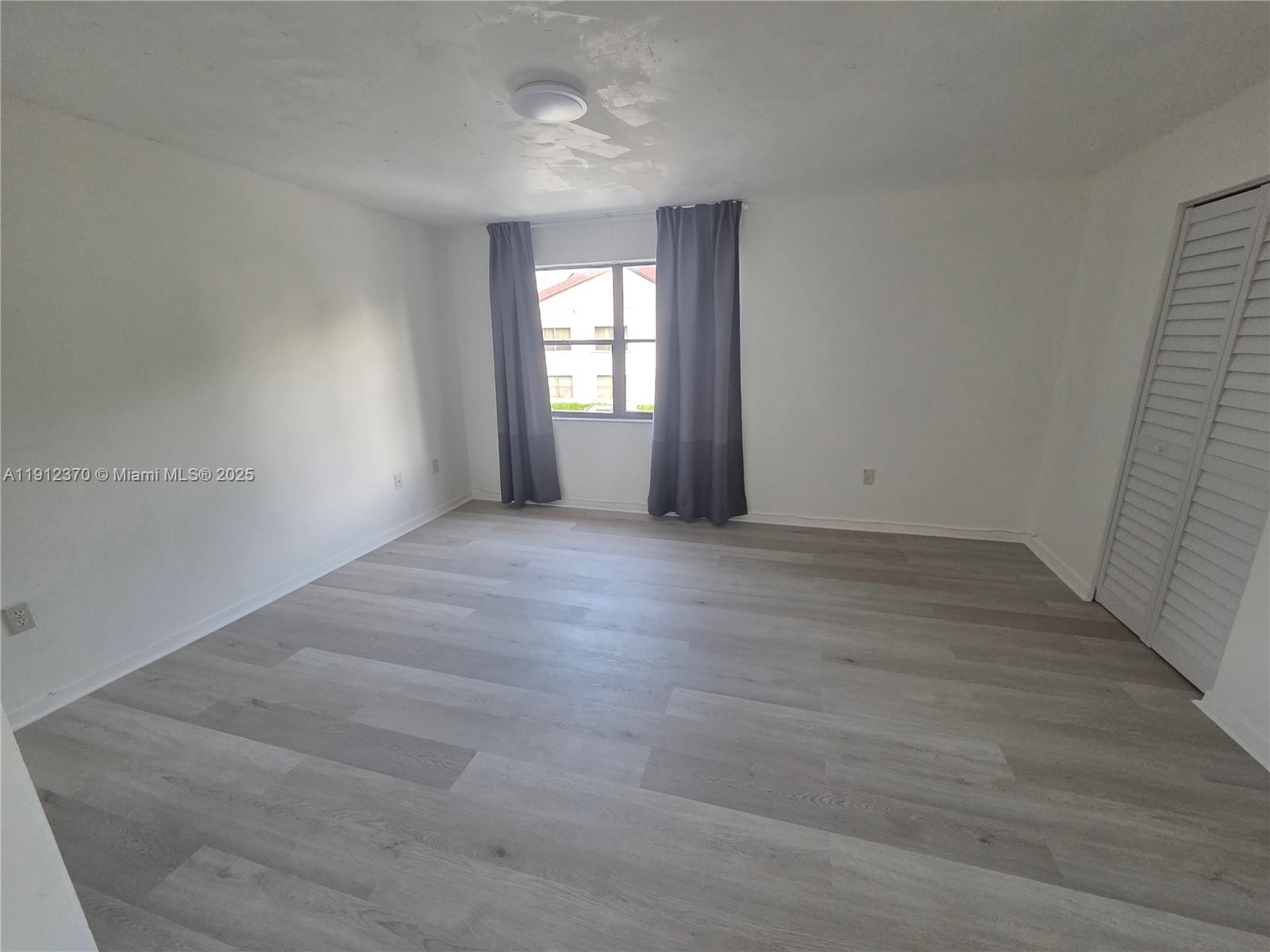 9433 Fontainebleau Boulevard, Unit 212 Miami, FL 33172 - Photo 16 of 45 wooden floor in an empty room with a window