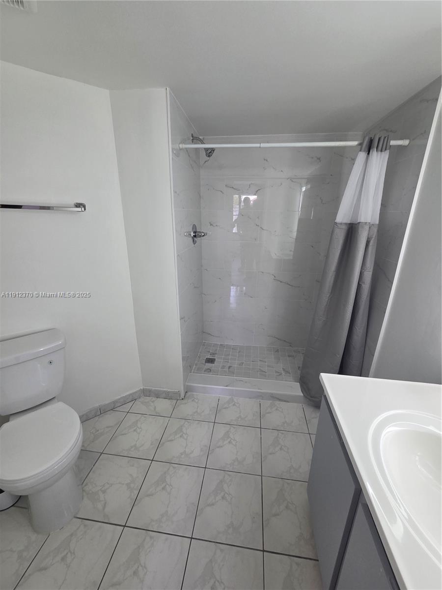 9433 Fontainebleau Boulevard, Unit 212 Miami, FL 33172 - Photo 18 of 45 a bathroom with a granite countertop shower and a toilet