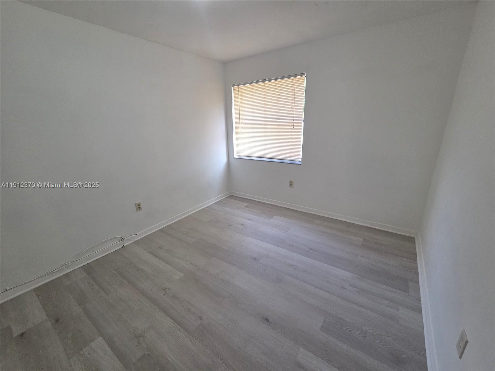 9433 Fontainebleau Boulevard, Unit 212 Miami, FL 33172 - Photo 25 of 45 an empty room with wooden floor and windows