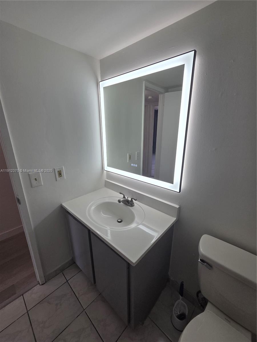 9433 Fontainebleau Boulevard, Unit 212 Miami, FL 33172 - Photo 29 of 45 a bathroom with a sink toilet and mirror