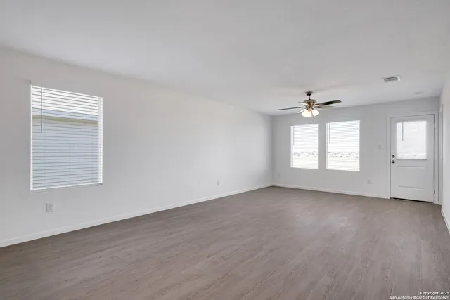 a view of an empty room with a window and wooden floor