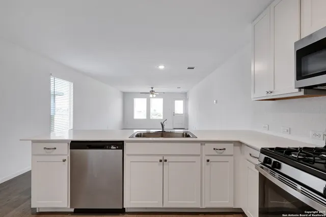 a kitchen with cabinets appliances a sink and a window