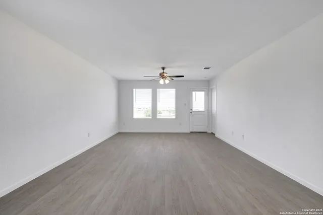 an empty room with wooden floor and windows