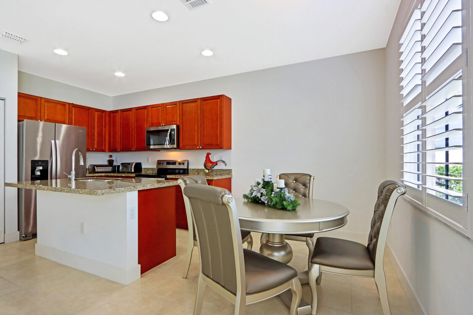 6024 Pine Tree Way Riviera Beach, FL 33410 - Photo 7 of 26 a kitchen with stainless steel appliances granite countertop a refrigerator a stove a sink a dining table and chairs with wooden floor