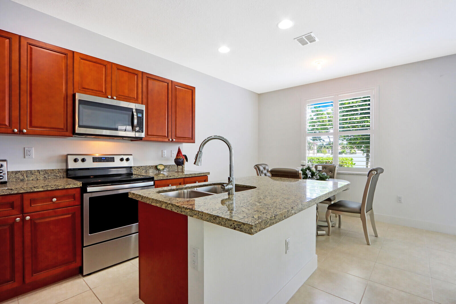6024 Pine Tree Way Riviera Beach, FL 33410 - Photo 8 of 26 a kitchen with granite countertop a stove top oven microwave and cabinets
