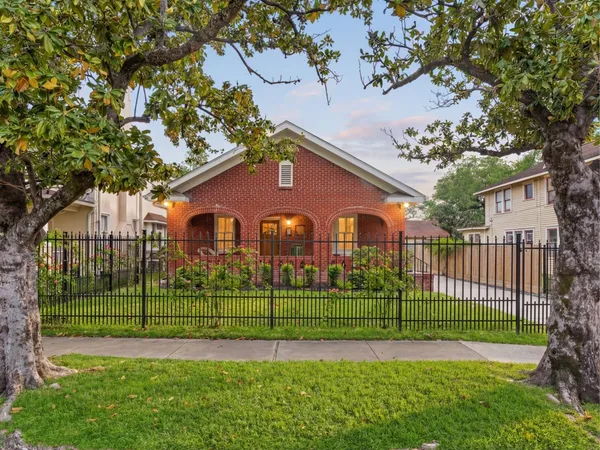 a view of a house with a big yard and potted plants and large trees