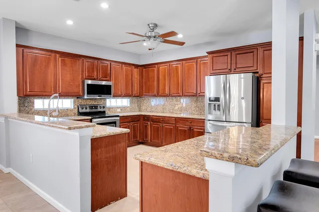 a kitchen with granite countertop wood cabinets stainless steel appliances and a sink