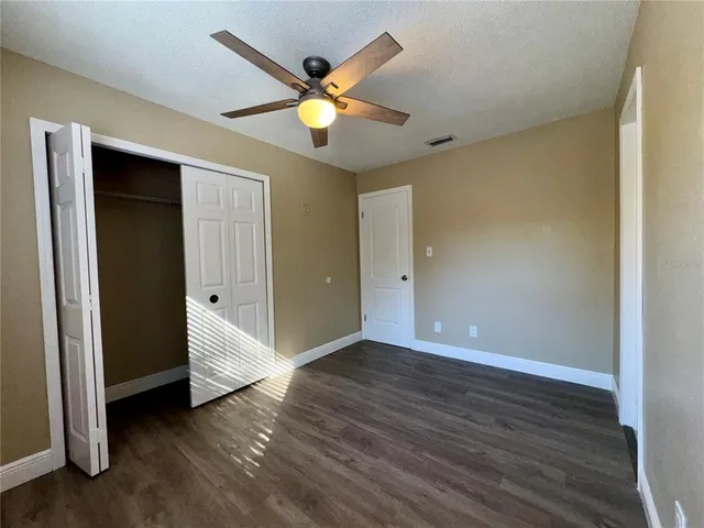 an empty room with wooden floor and fan