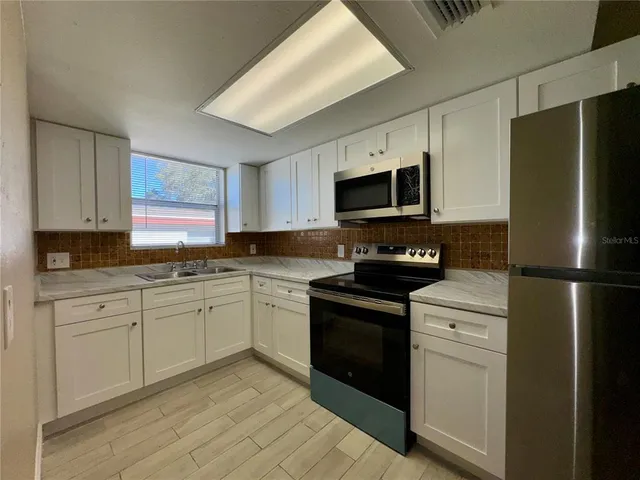 a kitchen with stainless steel appliances a sink dishwasher stove microwave and cabinets
