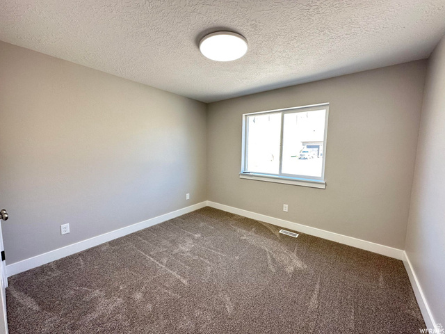 1171 West 2330 North Helper, UT 84526 - Photo 19 of 26 Spare room featuring dark carpet and a textured ceiling