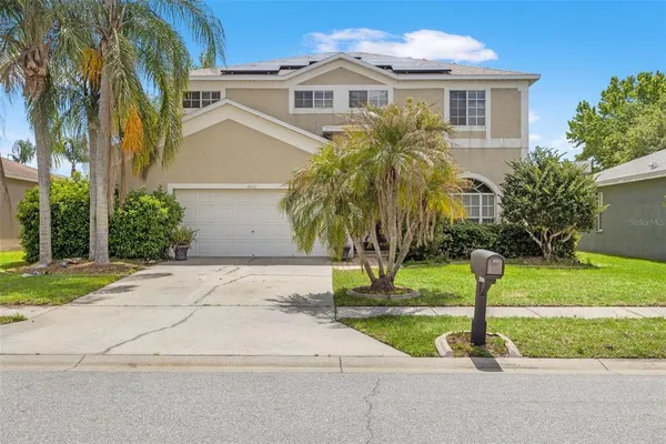 a view of a house with a yard and palm trees