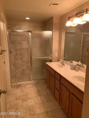 a bathroom with a double vanity sink mirror and shower