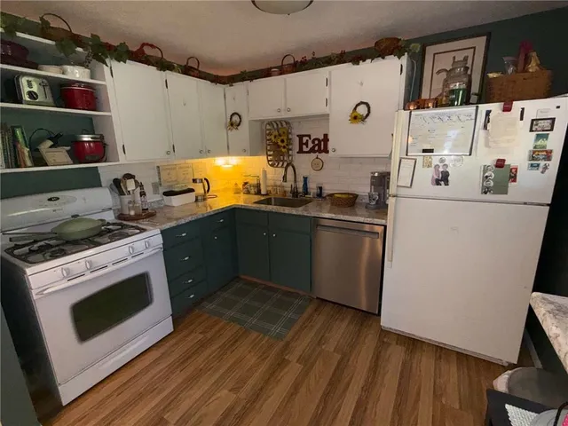 a kitchen with stainless steel appliances a stove a sink and wooden floor