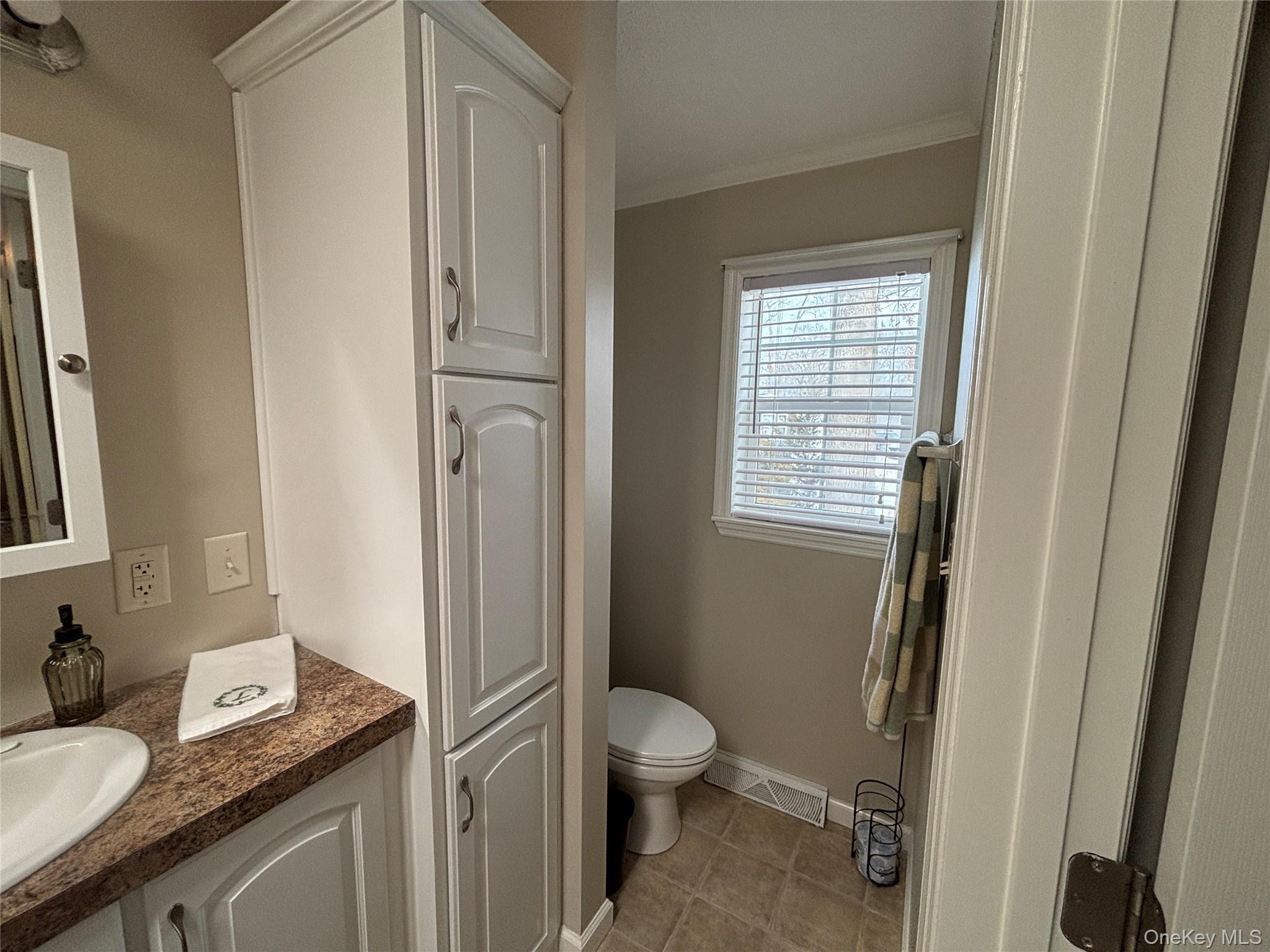 1661 Old Country Road, Unit 69 Riverhead, NY 11901 - Photo 24 of 37 a bathroom with a granite countertop toilet a sink and a mirror