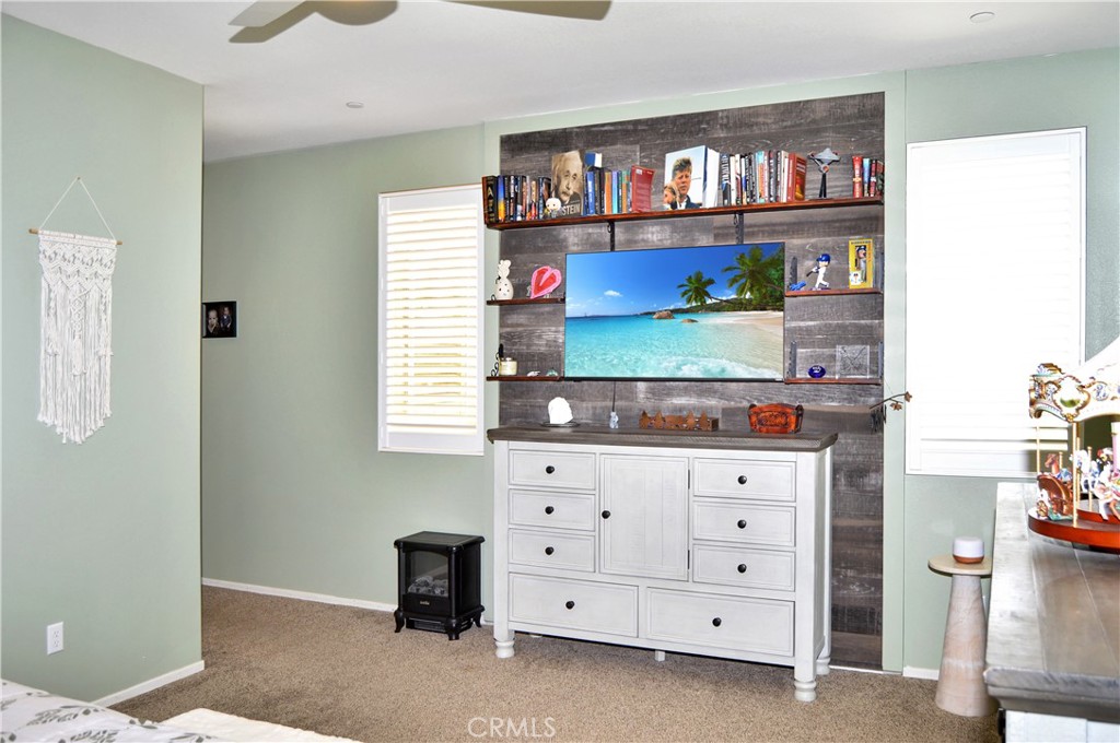 166 Fox Lane Calimesa, CA 92320 - Photo 35 of 76 Inviting Main Bedroom Suite with Custom Headboard with Reading Lights, Matching TV Surround with Shelving, Wood Panel Accents, a Ceiling Fan, and Cozy Carpeting (TV screen simulated)