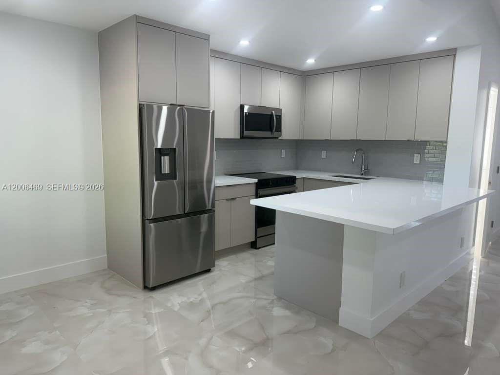 a kitchen with stainless steel appliances granite countertop a refrigerator a stove a sink and a microwave