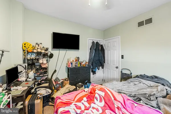 a bedroom with bed and a flat tv screen on the dresser