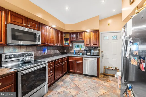 a kitchen with stainless steel appliances granite countertop a stove top oven a sink dishwasher a refrigerator and cabinets with wooden floor