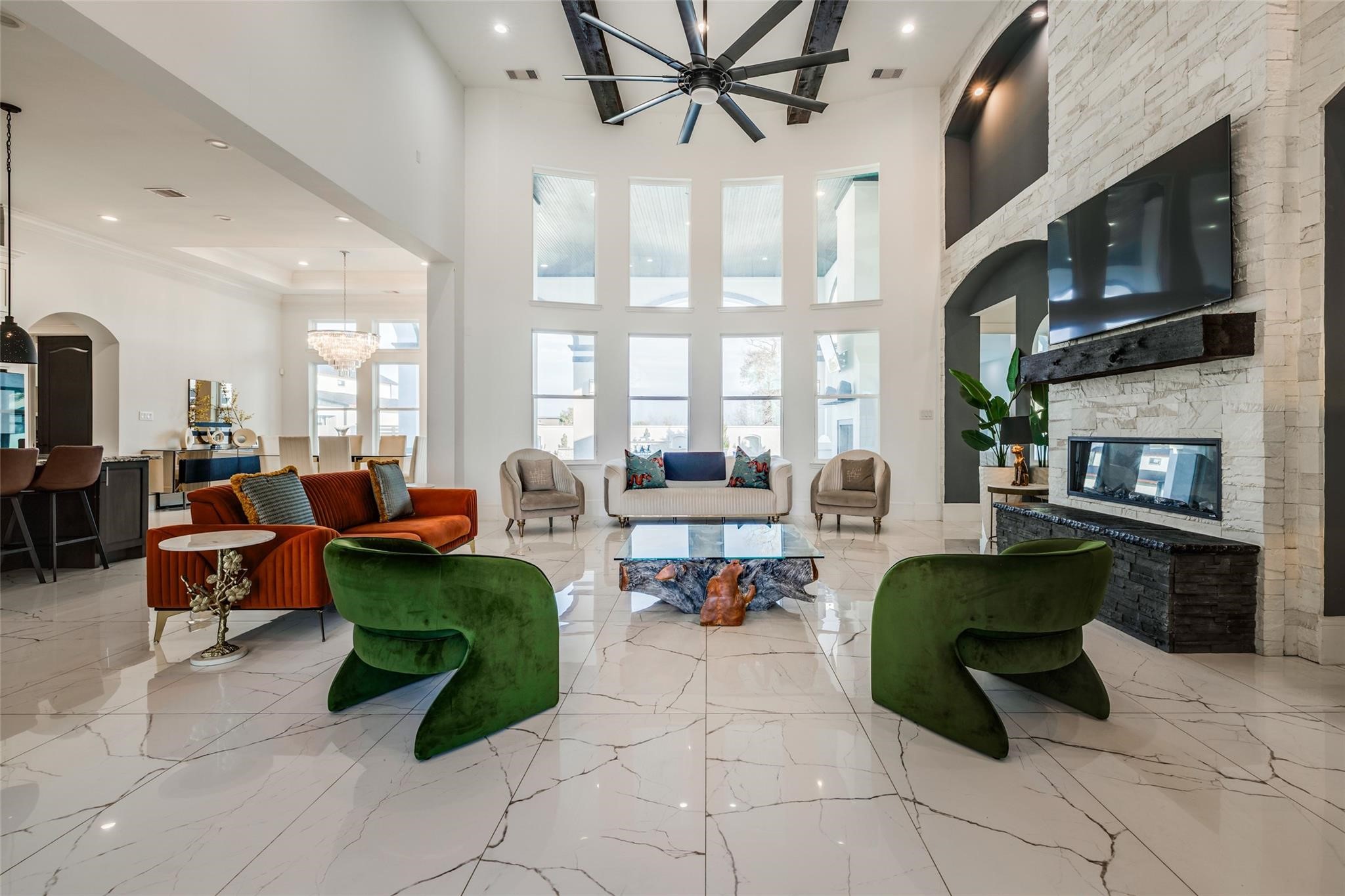 4821 Walters Road Richmond, TX 77469 - Photo 20 of 50 a perfect blend of modern luxury and warmth, highlighted by soaring vaulted ceilings with exposed beams, oversized windows that flood the home with natural light, and elegant designer finishes throughout. The open-concept layout features a striking floor-to-ceiling fireplace, custom built-ins, and seamless flow into the gourmet kitchen and dining areas, creating an ideal setting for both everyday living and entertaining. Thoughtfully curated furnishings, rich wood accents, and sophisticated lighting