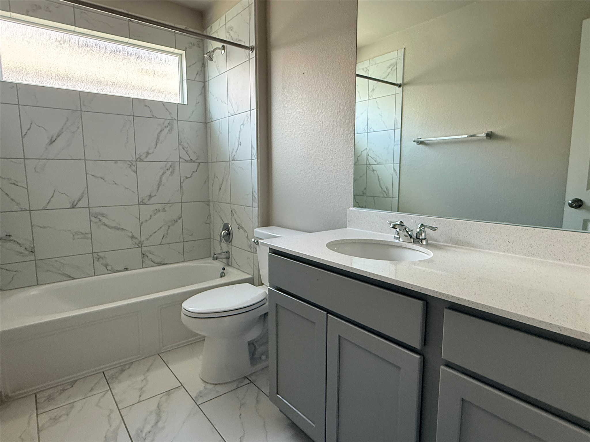129 Perfect World Loop Jarrell, TX 76537 - Photo 26 of 31 A refined bathroom featuring a contemporary vanity, elegant marble-style tile, and a practical shower-tub combination.