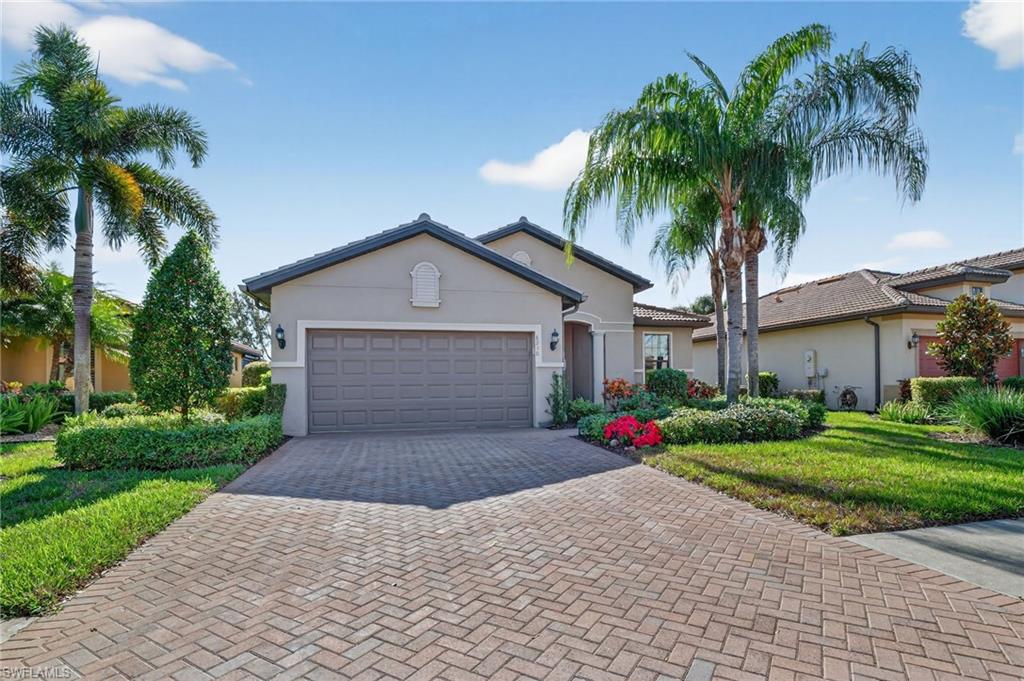 Ranch-style house featuring stucco siding, decorative driveway, a garage, and a front lawn