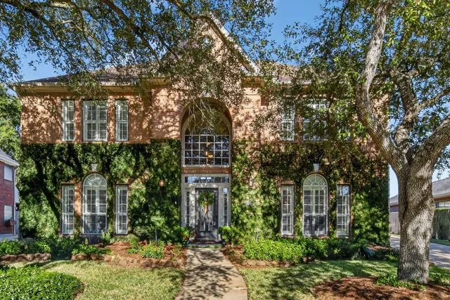 a view of a big house with large trees and plants