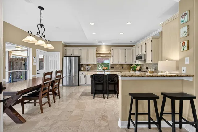 a large kitchen with stainless steel appliances granite countertop a stove top oven a sink dishwasher and white cabinets with wooden floor