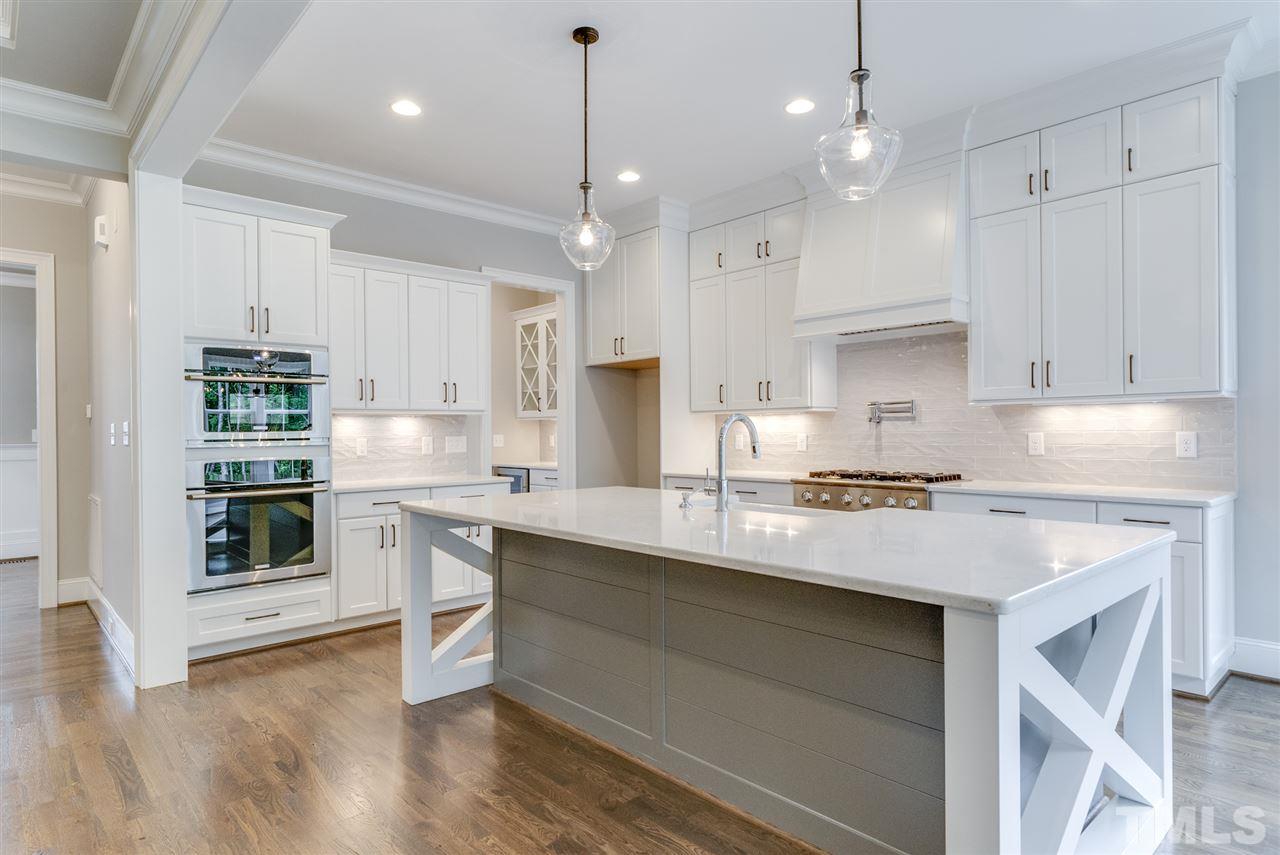 113 Roseroot Court Holly Springs, NC 27540 - Photo 6 of 25 a kitchen with stainless steel appliances granite countertop a stove a sink and white cabinets with wooden floors