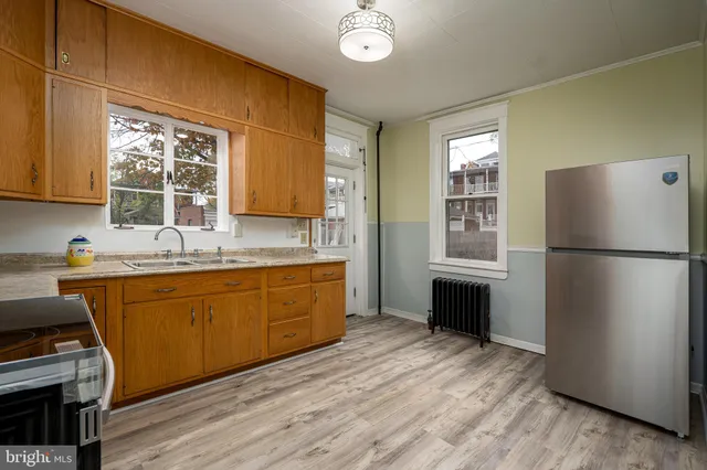 a kitchen with stainless steel appliances granite countertop a refrigerator a sink dishwasher a stove a dining table and chairs with wooden floor