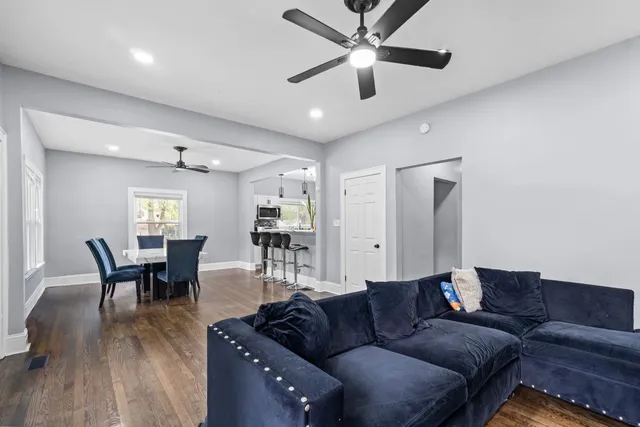 a living room with furniture and a dining table with wooden floor