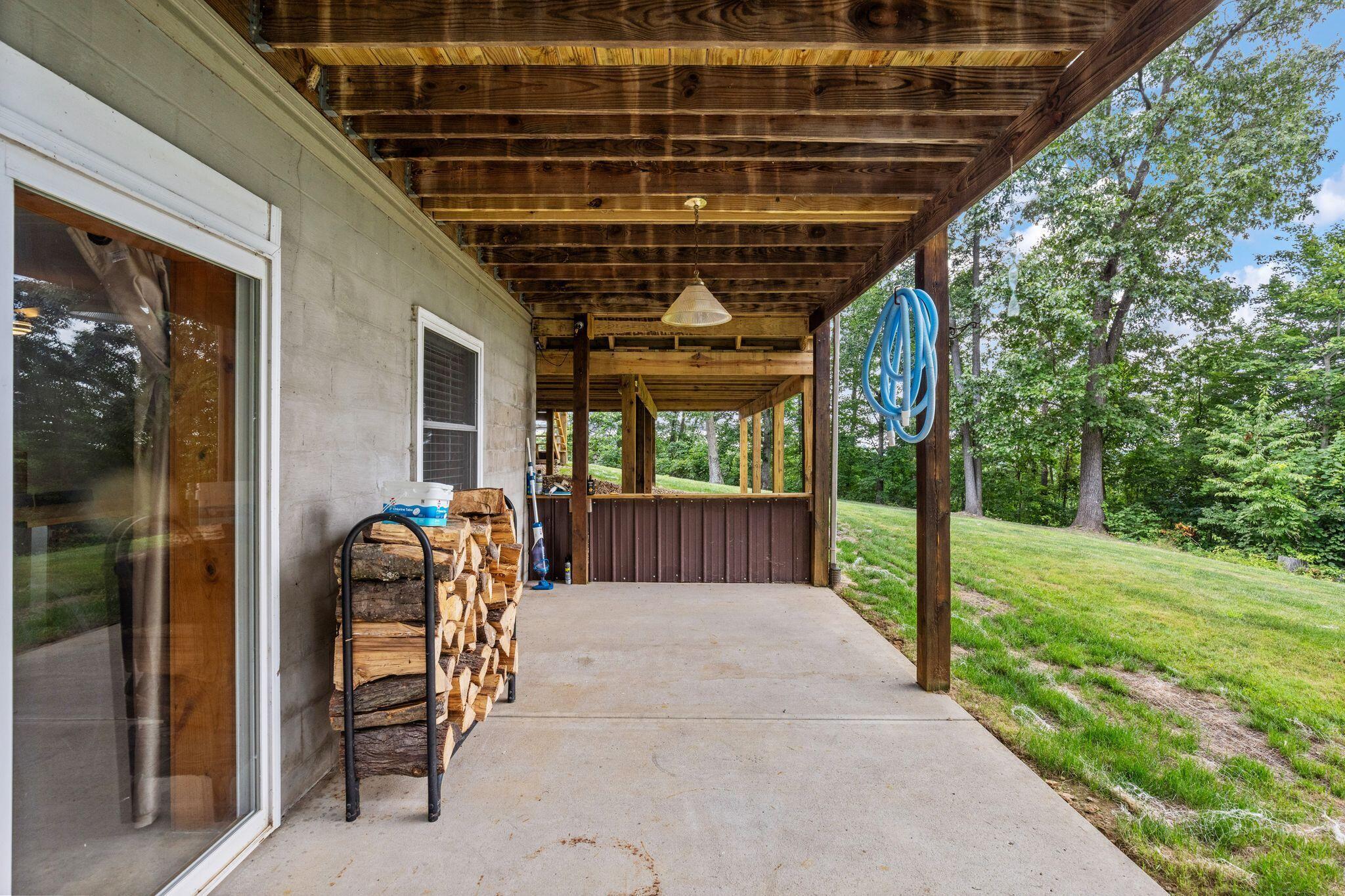 10446 Rich Hollow Road Southwest Lancaster, OH 43130 - Photo 72 of 83 Expansive covered patio featuring a concrete surface, exposed wood ceiling beams, and a sliding glass door