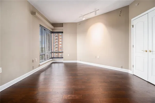 a view of an empty room with wooden floor and a window