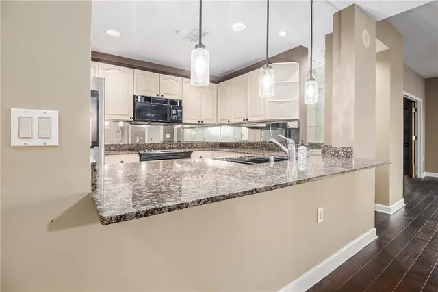 a kitchen with stainless steel appliances granite countertop a sink a stove and a wooden floors