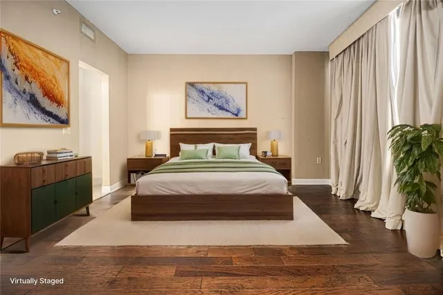 a bedroom with a large bed a rug and potted plant