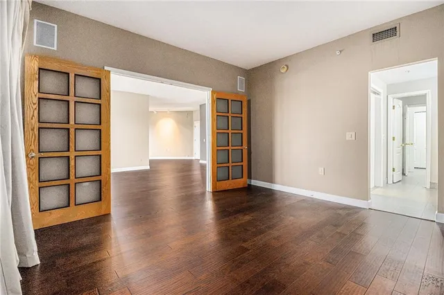 a view of an empty room with wooden floor and cabinets