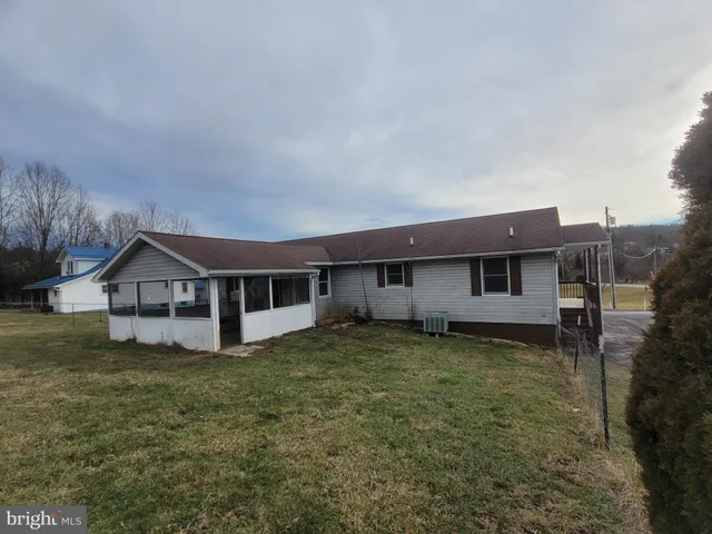 a house that is sitting in the grass with large trees