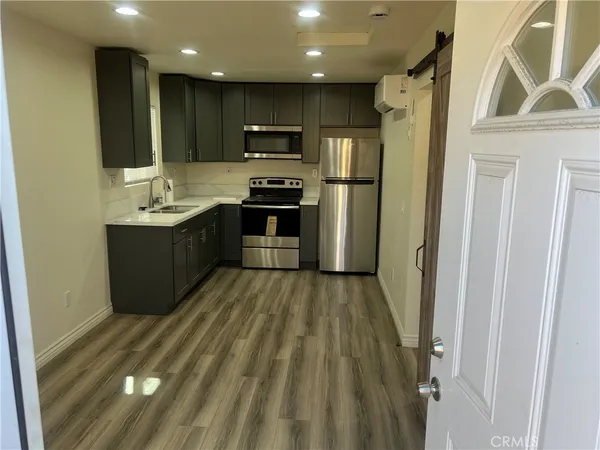 a kitchen with stainless steel appliances granite countertop a refrigerator a sink dishwasher a stove and a microwave oven with wooden floor