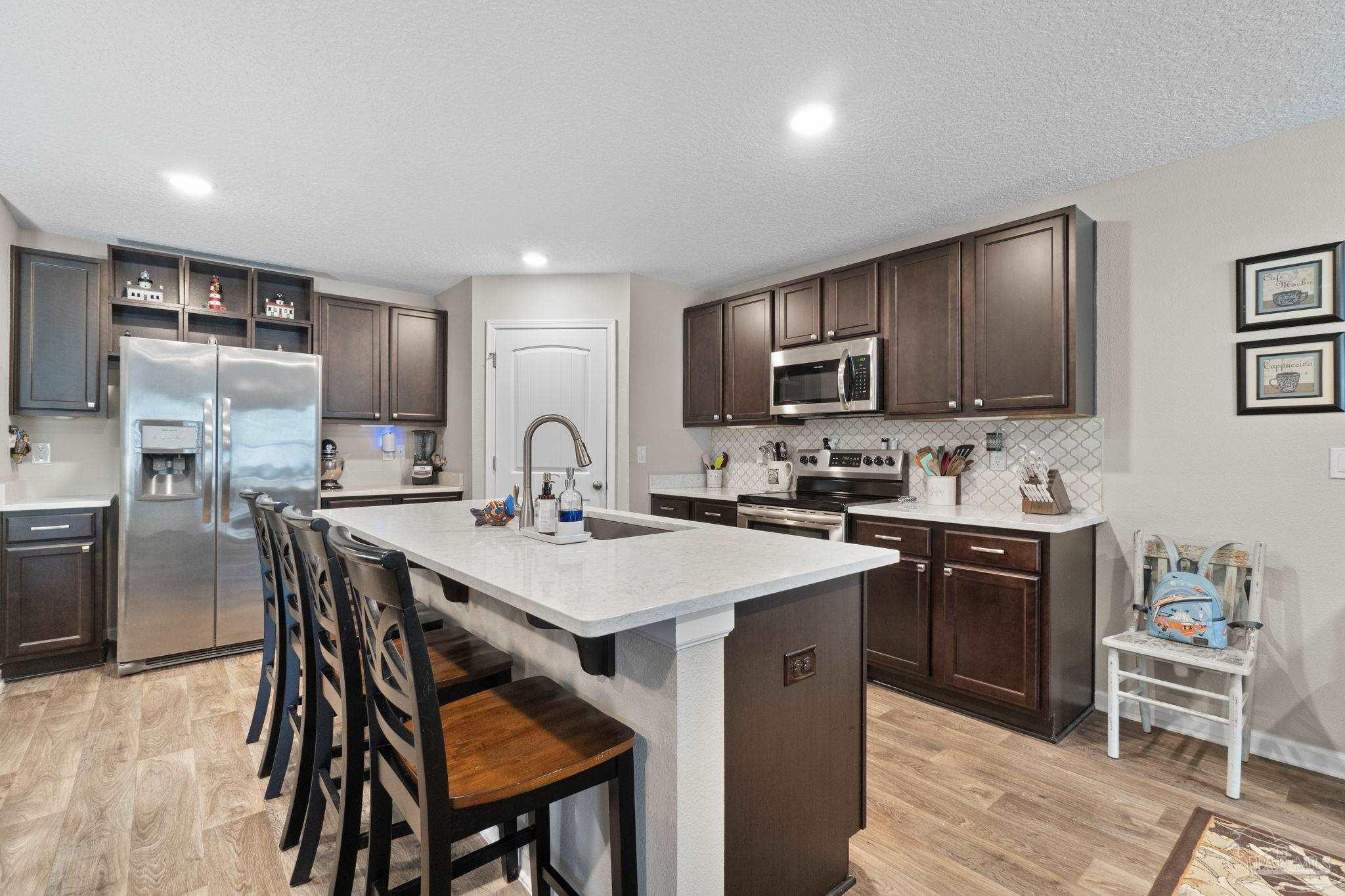 4082 Chickadee Street Milton, FL 32583 - Photo 10 of 43 a kitchen with stainless steel appliances granite countertop a table chairs sink refrigerator and cabinets