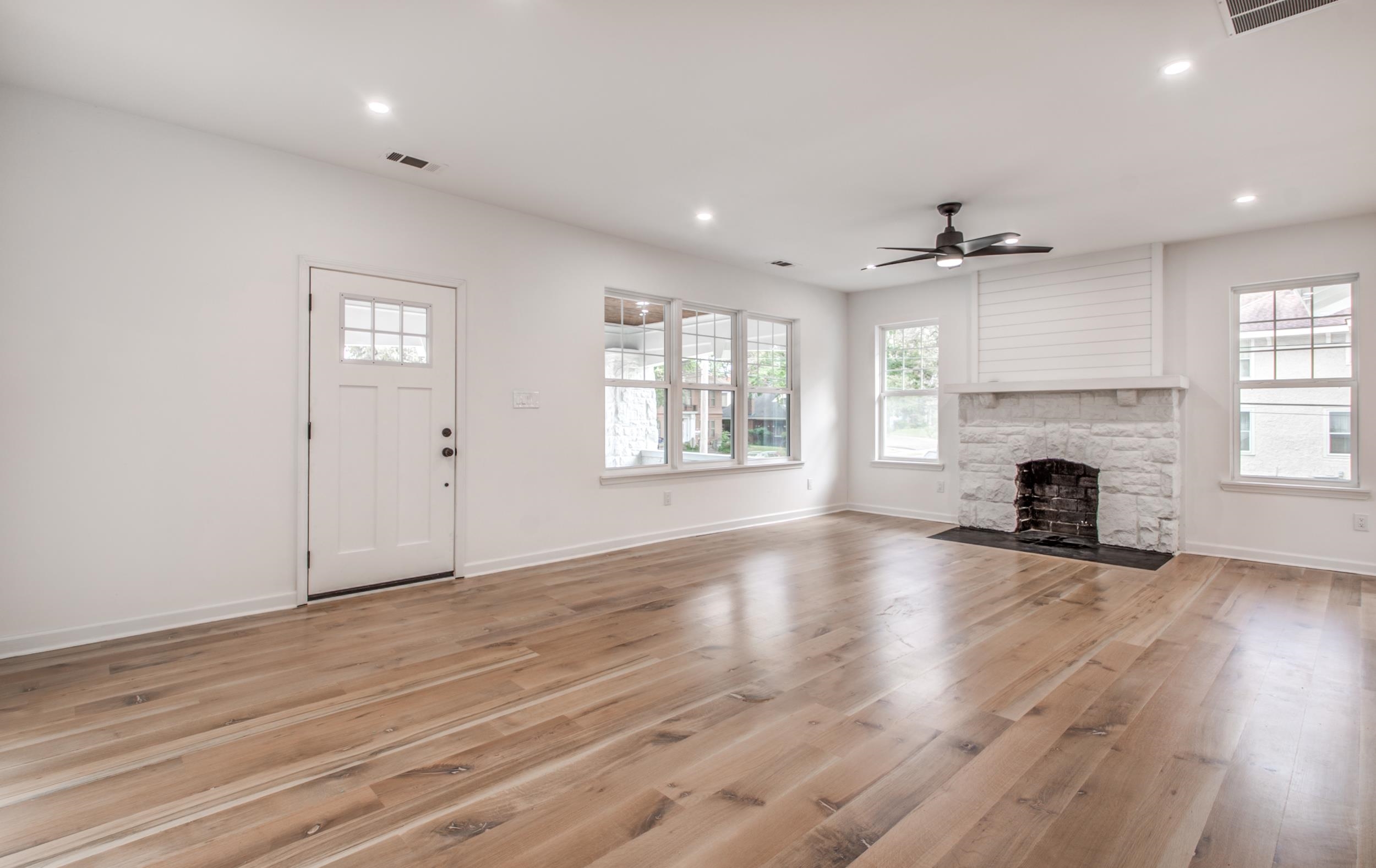 1781 Forest Avenue Memphis, TN 38112 - Photo 4 of 30 Unfurnished living room with light wood-type flooring, a stone fireplace, ceiling fan, healthy amount of natural light, and recessed lighting