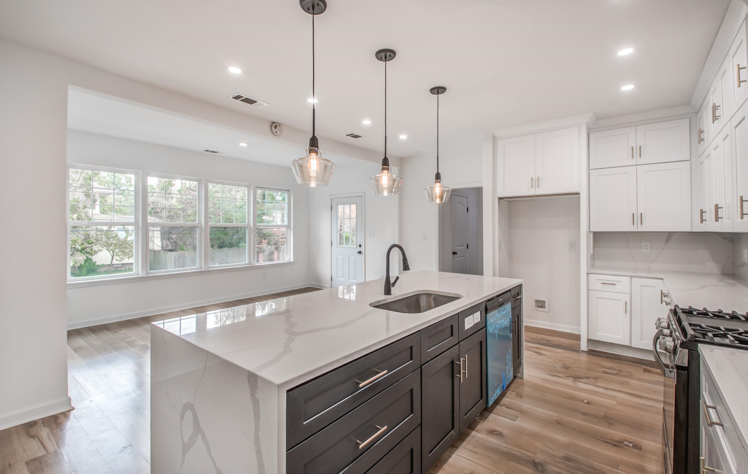 1781 Forest Avenue Memphis, TN 38112 - Photo 7 of 30 Kitchen with white cabinetry, light stone countertops, light wood finished floors, pendant lighting, and a center island with sink