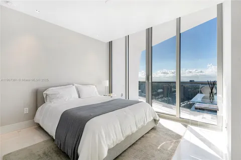 a bedroom with a large window and a glass door